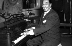 Duke Ellington, a famous jazz musician, poses with his piano at the KFG Radio Studio.